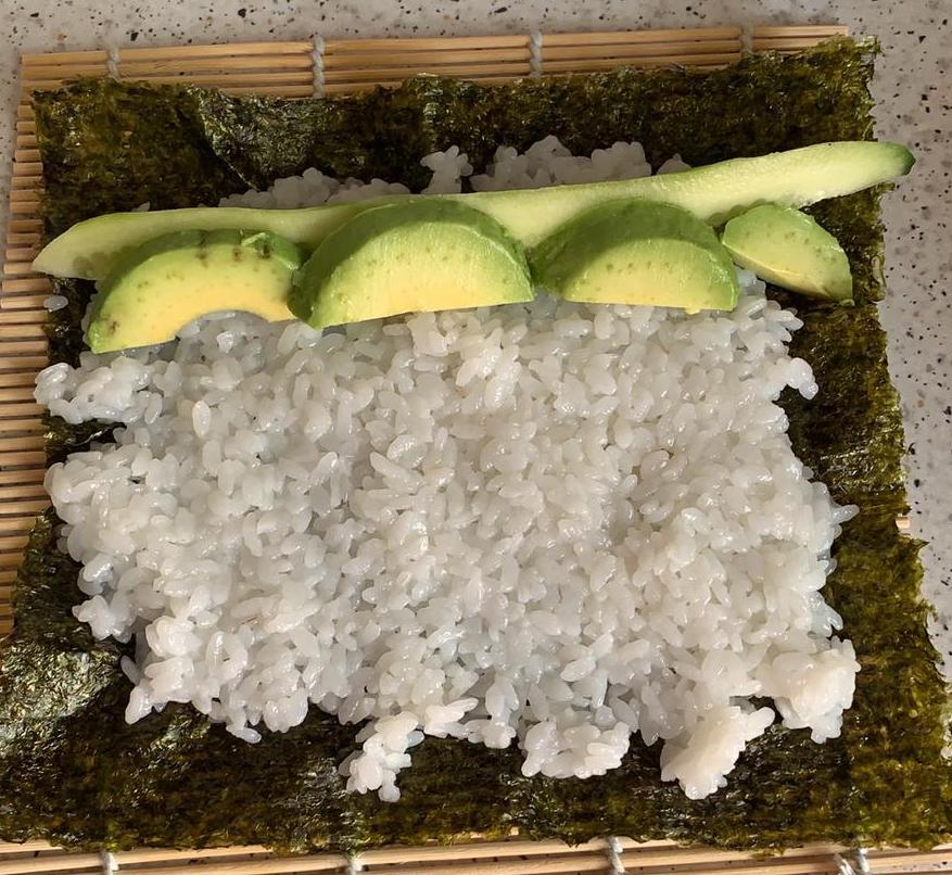 Montando un maki de sushi vegetariano con pepino y aguacate