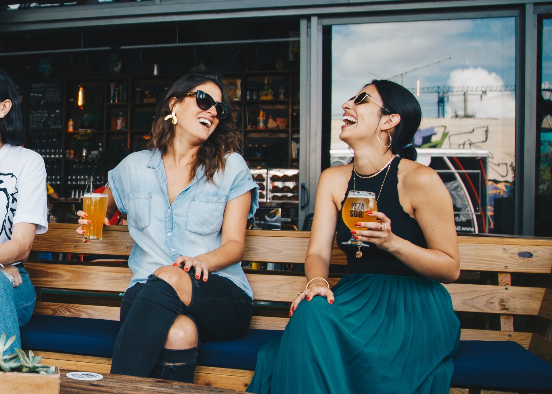 Chicas riéndose sentadas tomando una cerveza