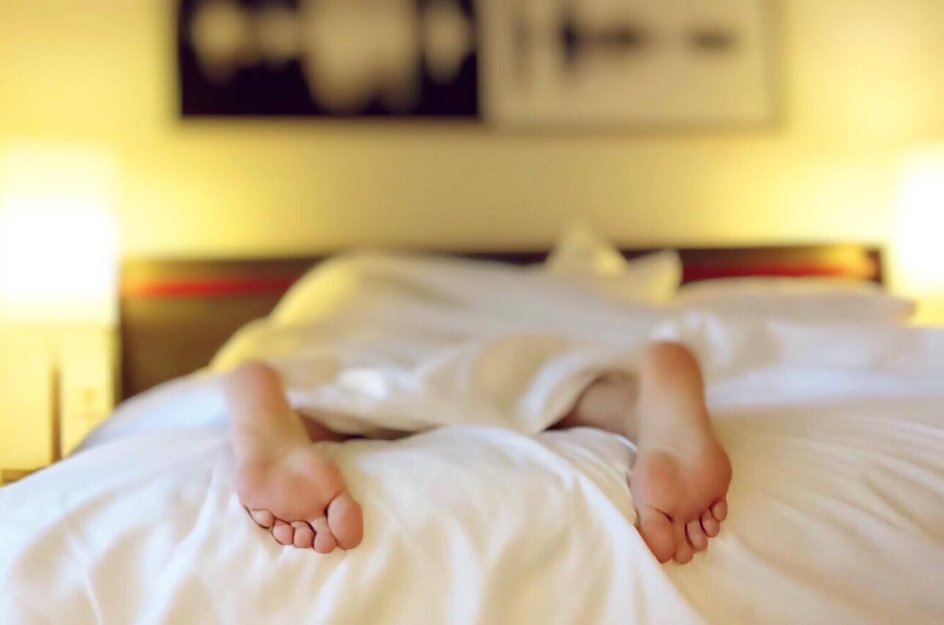 Persona durmiendo con los pies por fuera de las sábanas.