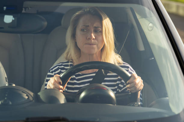 Mujer al volante con cara de preocupación.