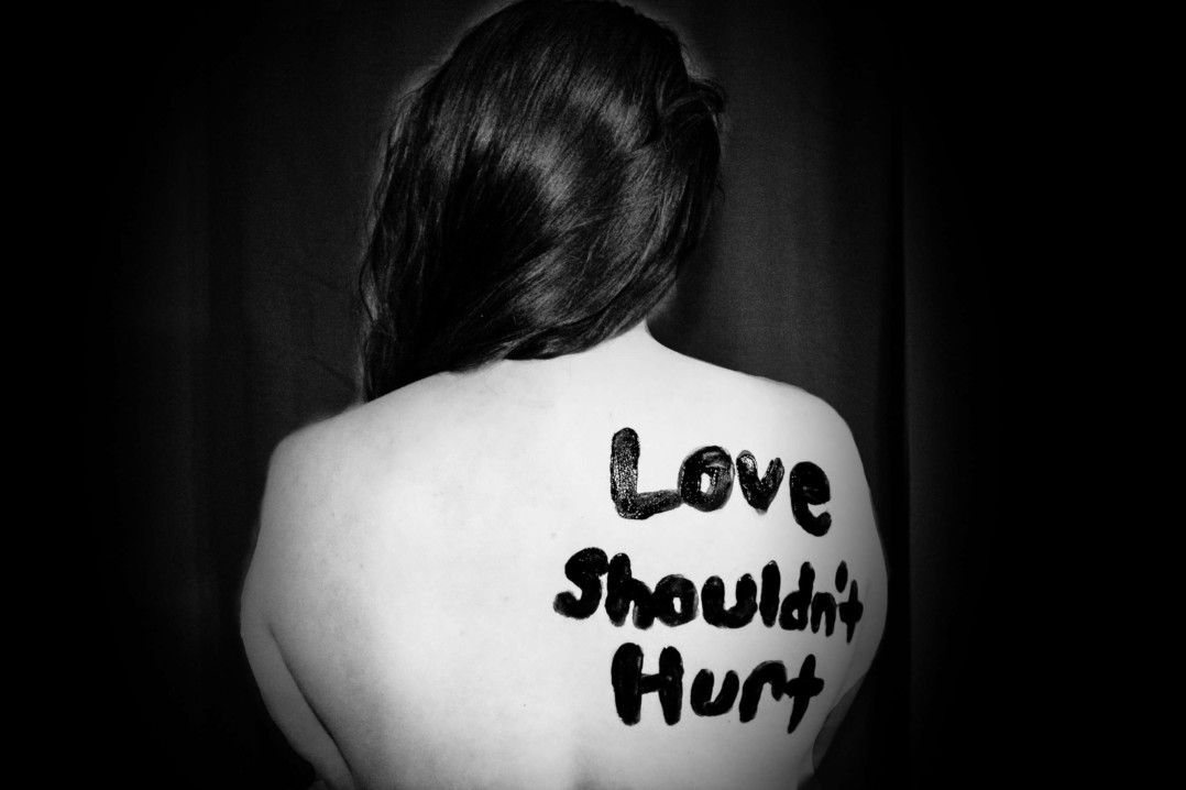 Mujer de espaldas con el texto Love shouldn't hurt.