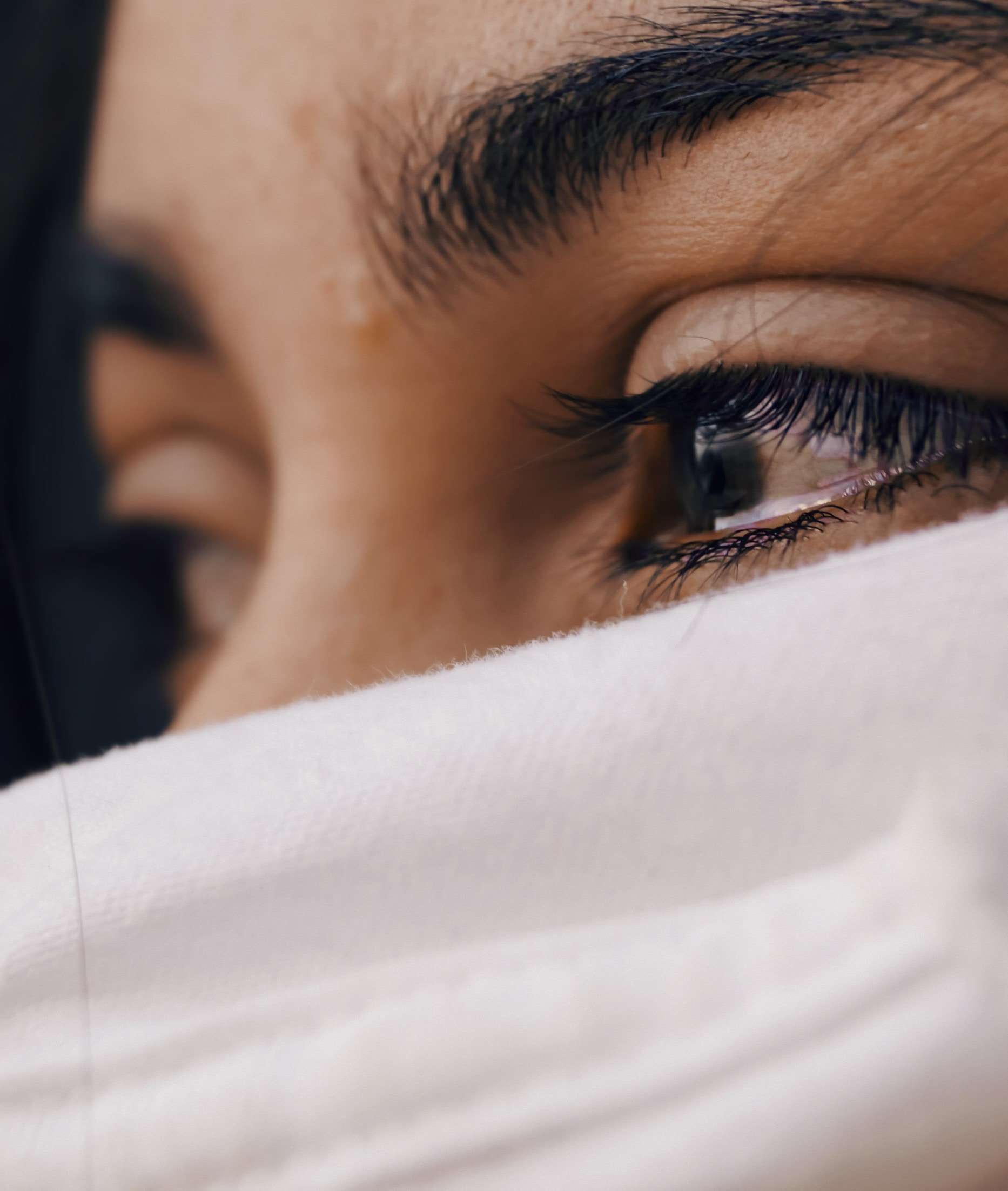 Ojos de mujer con lágrimas y mascarilla blanca.