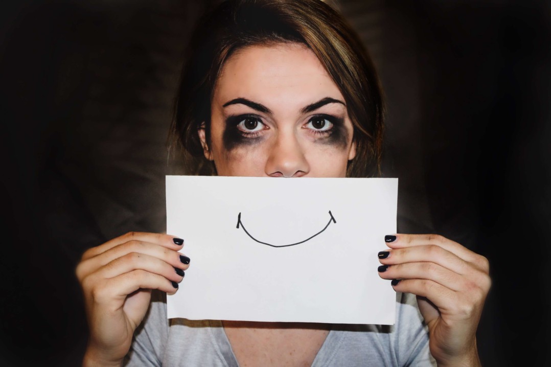 Mujer sujeta un papel con una sonrisa pintada.