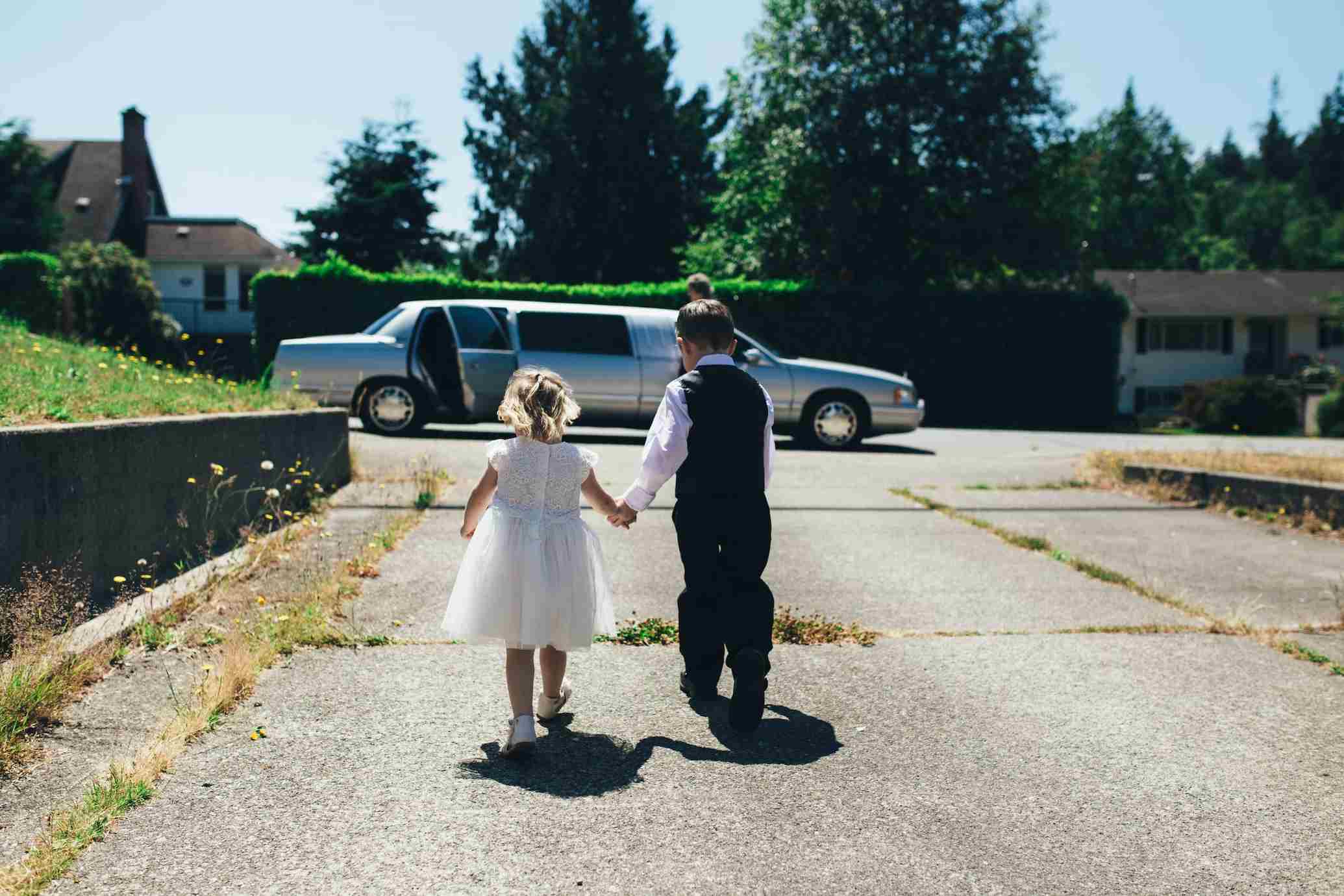 Dos ni&ntilde;os vestidos de novios pasean de la mano.